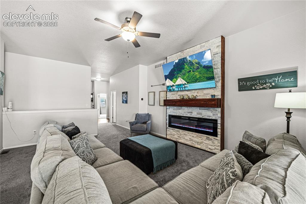 Image 14 of 50: Living space featuring a stone-clad electric fireplace with a wood mantle, 