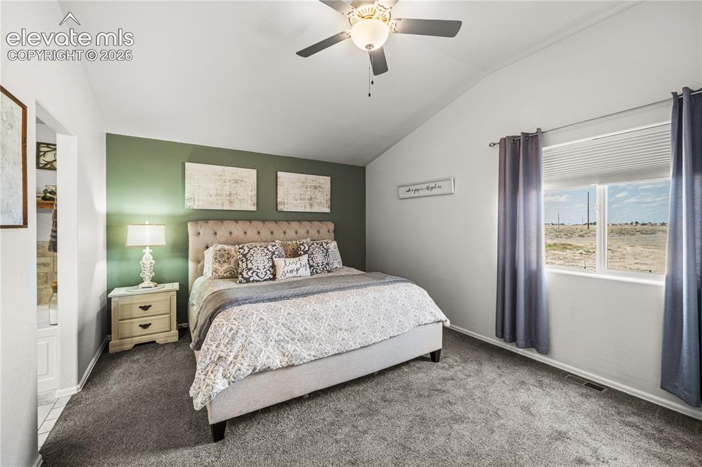Image 16 of 50: Carpeted room featuring a vaulted ceiling with a ceiling fan, a window, and