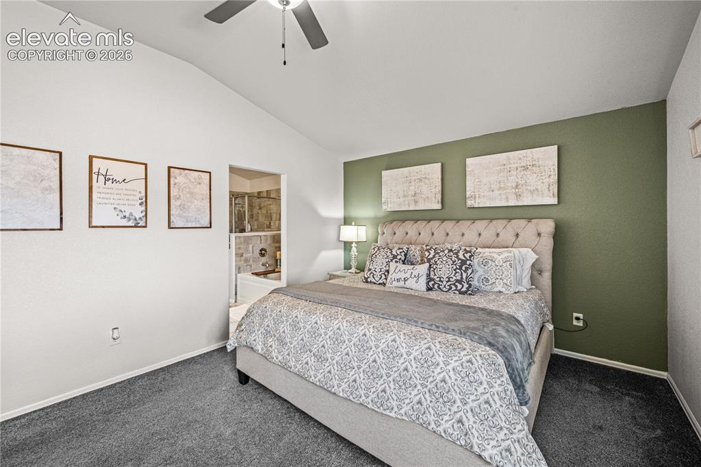 Image 17 of 50: Vaulted ceiling bedroom with a ceiling fan, carpet flooring, and a dedicate