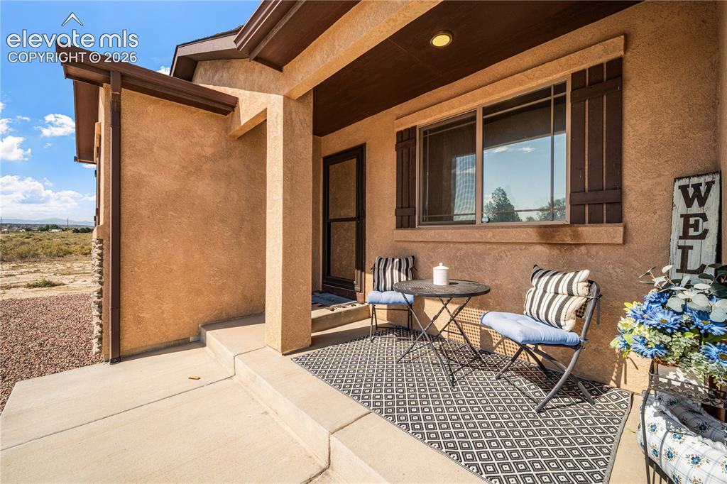 Image 2 of 50: Inviting covered front porch with stucco exterior and decorative shutters
