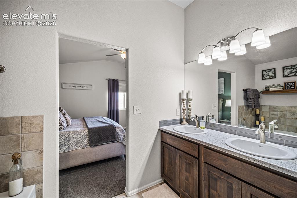 Image 20 of 50: Dual vanity with undermount sinks, speckled countertop, and dark wood-finis