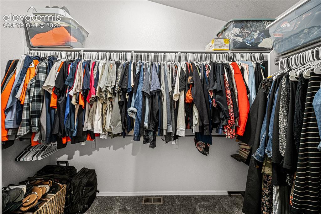 Image 25 of 50: Built-in closet system featuring multiple hanging rods and overhead shelvin
