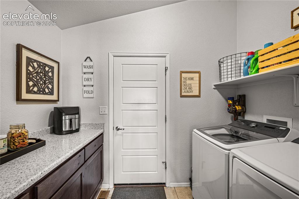 Image 26 of 50: Dedicated laundry area featuring a white multi-panel door, dark wood-finish