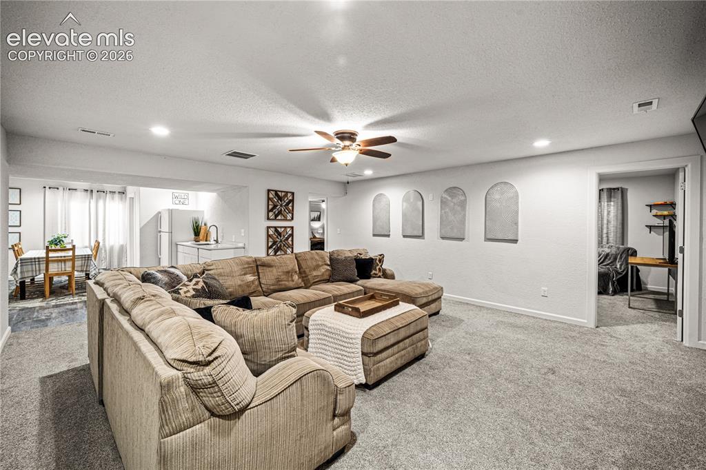 Image 29 of 50: Spacious living area featuring grey carpeting and recessed lighting