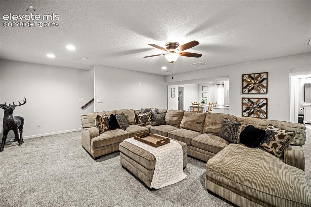 Image 30 of 50: Spacious living area featuring light gray carpeting, recessed lighting, and