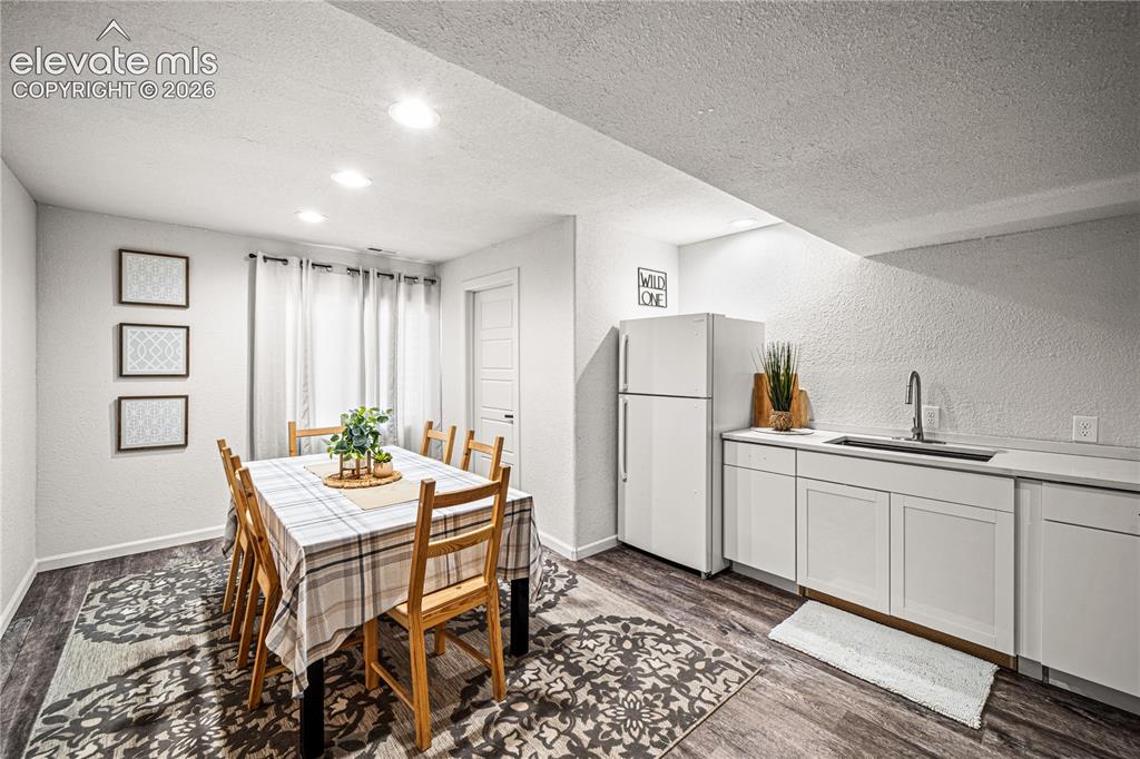 Image 34 of 50: Lower-level kitchenette and dining space featuring wood-finish flooring