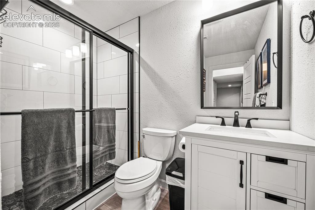 Image 39 of 50: Bathroom featuring a glass-enclosed shower with black trim, white subway ti