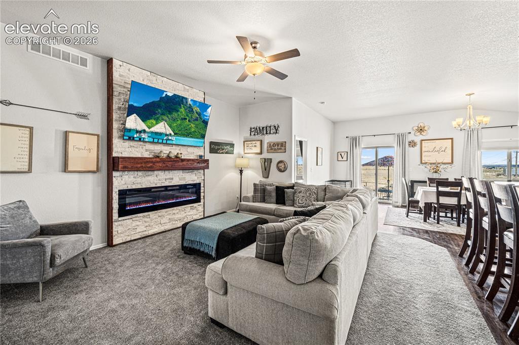 Image 4 of 50: Spacious open-concept living area featuring a stone-clad fireplace with a r