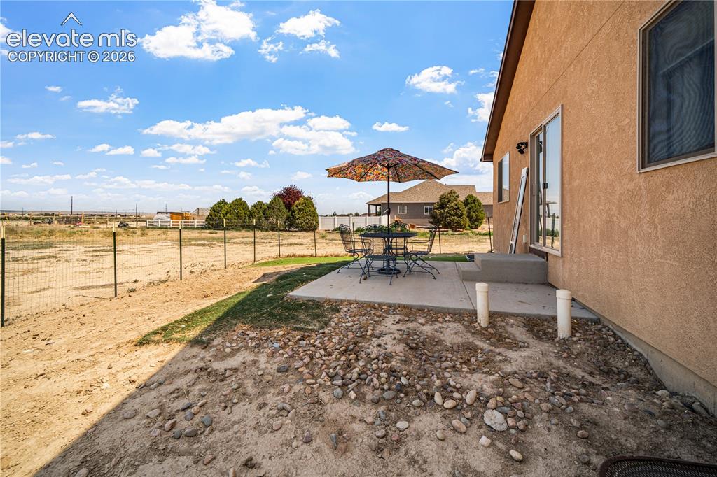 Image 41 of 50: Exterior patio area featuring stucco siding, a sliding glass door, and a co