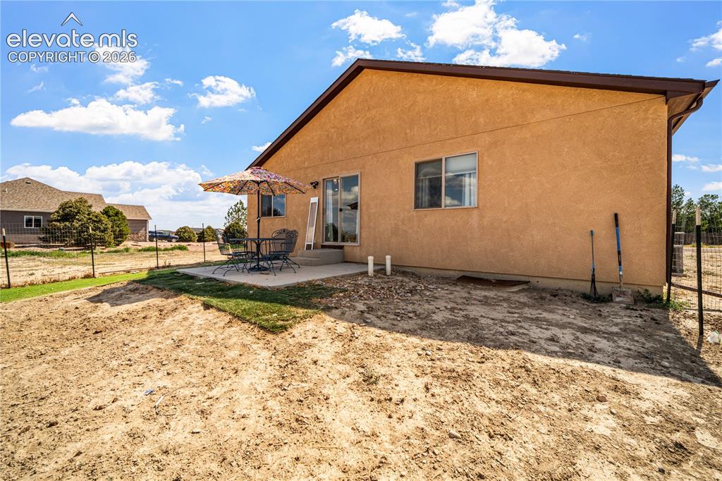 Image 42 of 50: Rear exterior featuring a stucco finish, a concrete patio, and a sliding gl