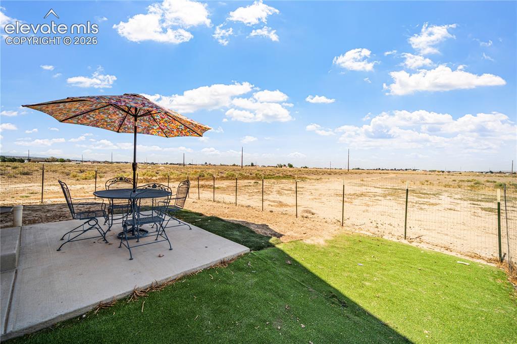 Image 43 of 50: Outdoor patio featuring a concrete slab, artificial turf, and wire fencing