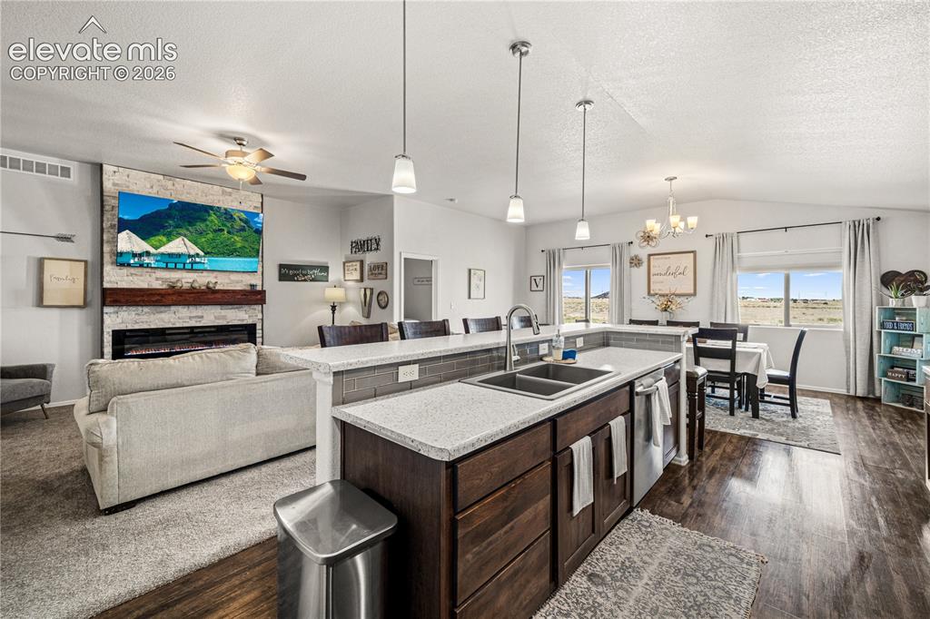 Image 5 of 50: Open-concept living area featuring a kitchen island with dual sinks and pen