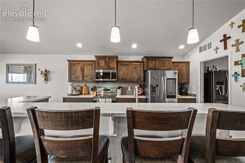 Image 7 of 50: Kitchen featuring a large island with a light-colored countertop, recessed 