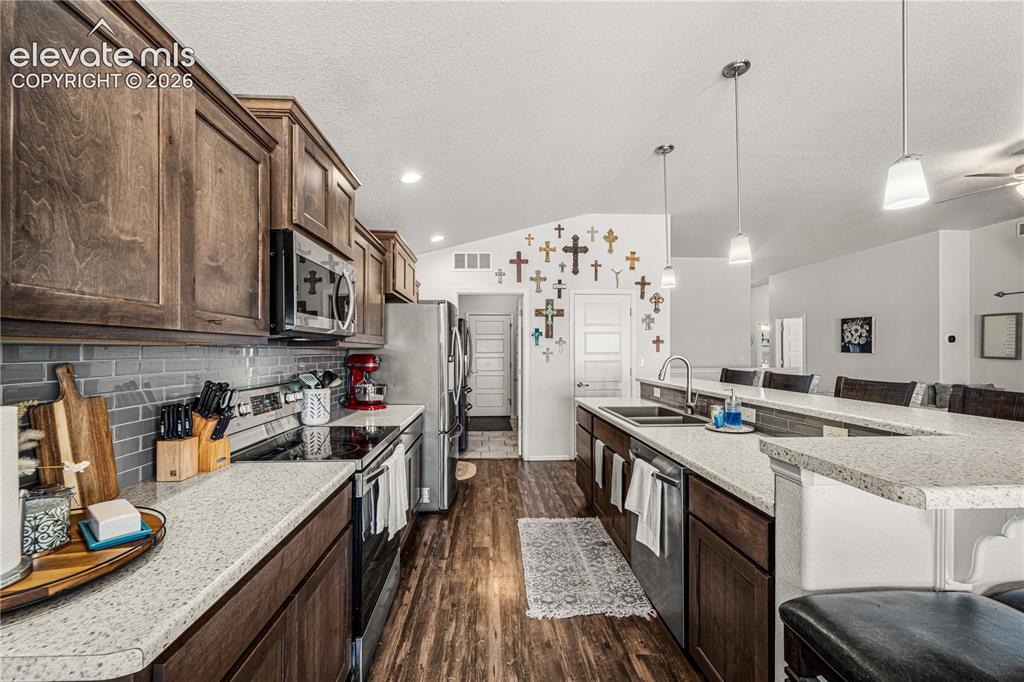 Image 8 of 50: Spacious kitchen featuring wood-finish flooring, dark wood cabinetry, and l