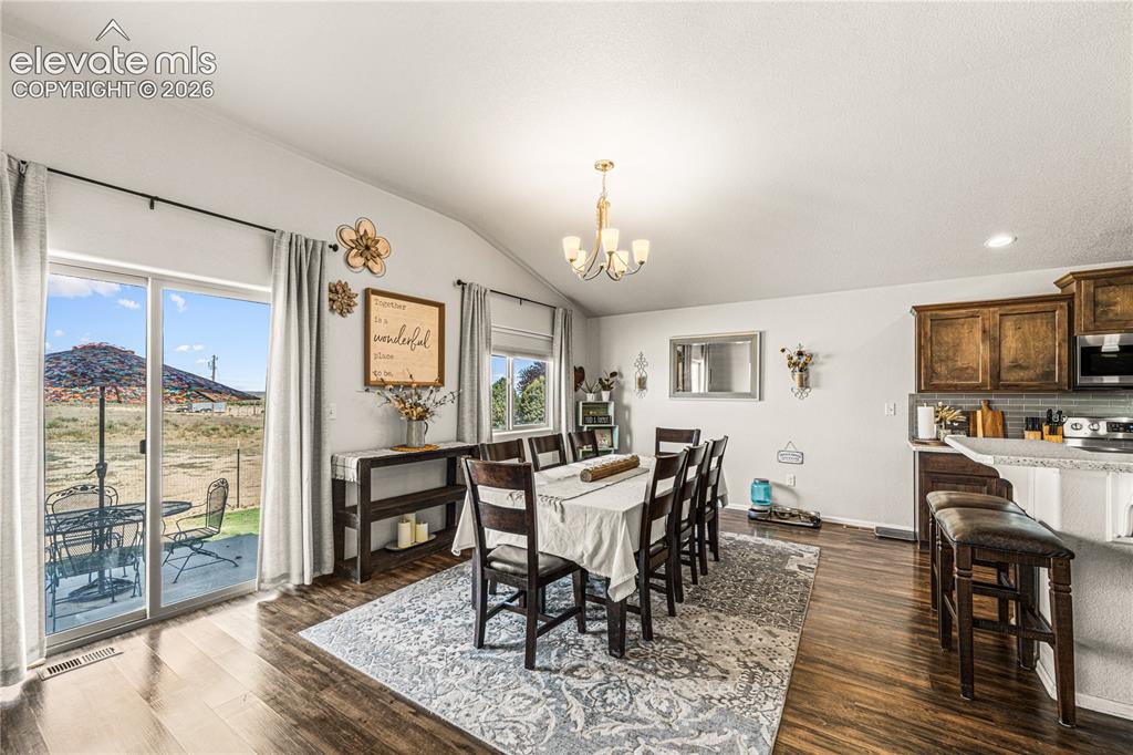 Image 9 of 50: Open concept dining area featuring wood-finish flooring, a vaulted ceiling,