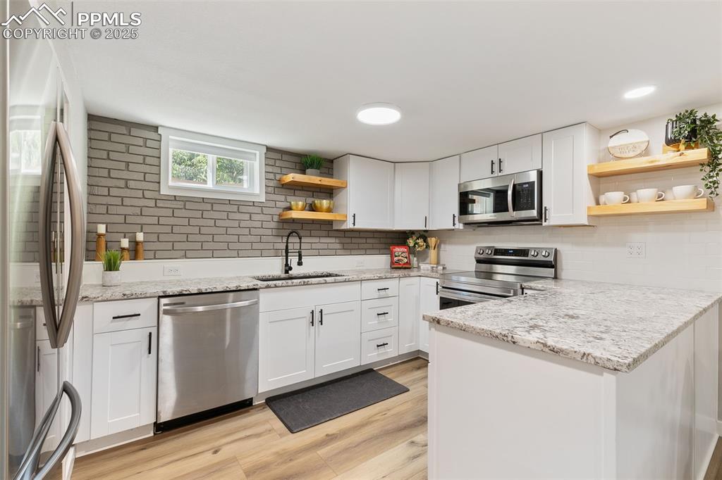 Image 23 of 37: Kitchen featuring open shelves, stainless steel appliances, white cabinetry