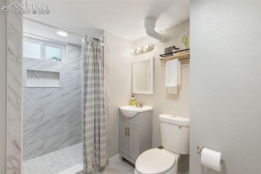 Image 31 of 37: Full bathroom featuring vanity, a stall shower, light marble finish floors,