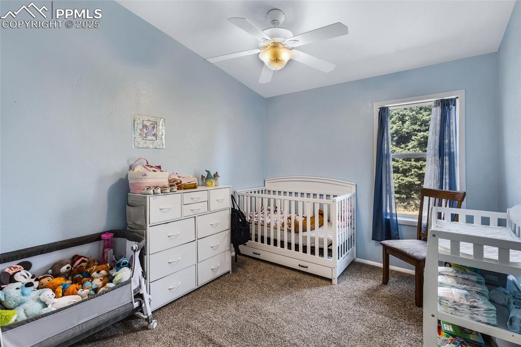Image 15 of 24: Carpeted bedroom featuring a nursery area and a ceiling fan