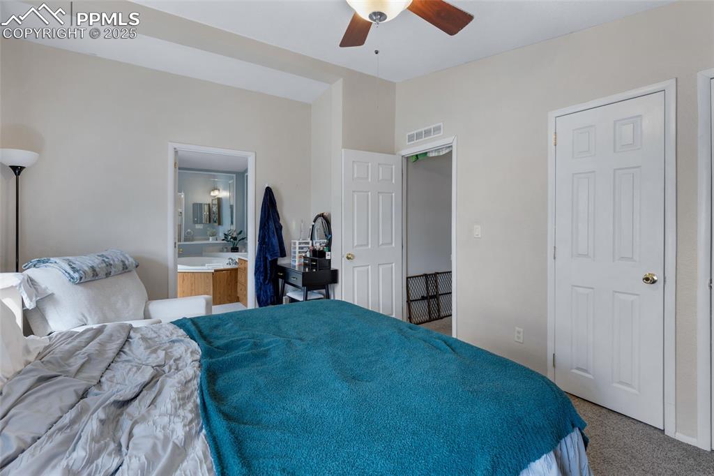 Image 17 of 24: Bedroom with carpet flooring, a ceiling fan, and ensuite bathroom