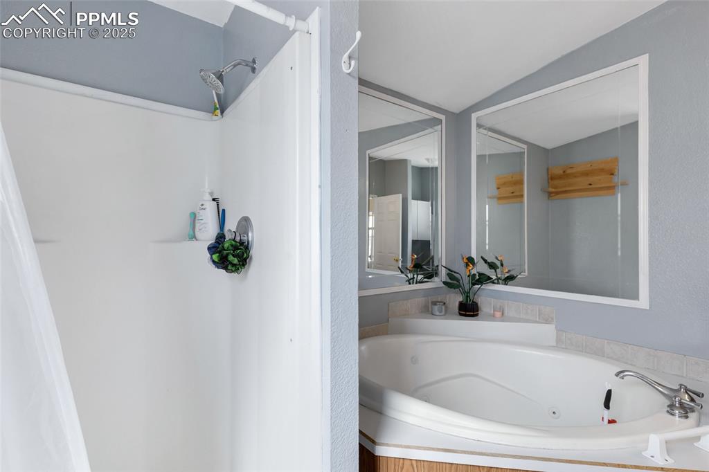 Image 19 of 24: Bathroom with a whirlpool tub, a shower, and vaulted ceiling