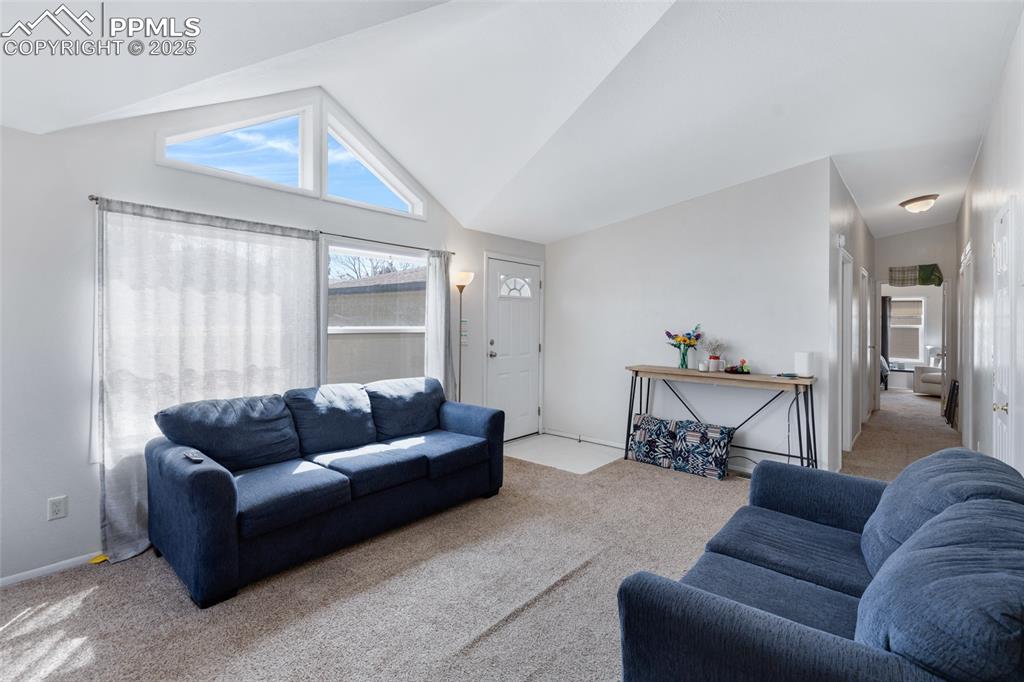 Image 6 of 24: Living room with light carpet and high vaulted ceiling
