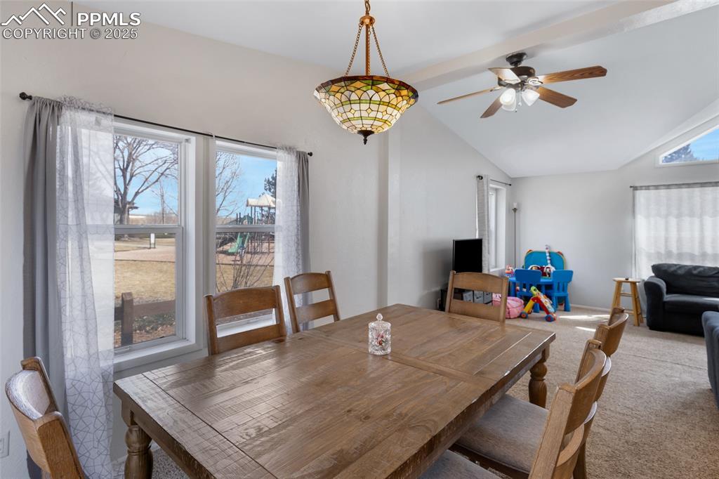 Image 9 of 24: Carpeted dining area with vaulted ceiling and a ceiling fan