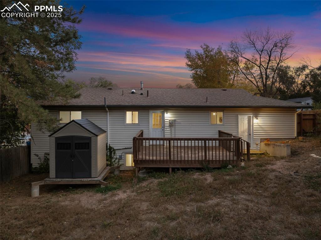 Image 10 of 47: Back of property with a shed, a wooden deck, and roof with shingles