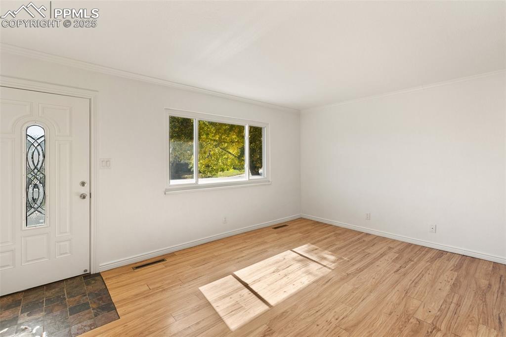 Image 15 of 47: Foyer with crown molding and light wood finished floors