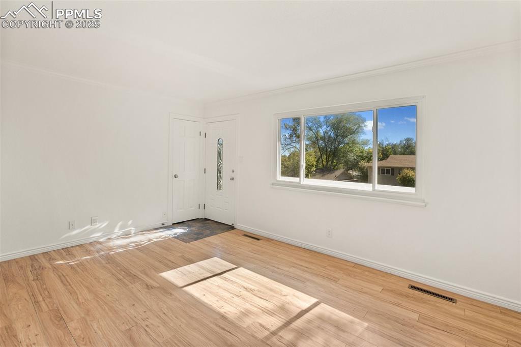 Image 16 of 47: Foyer entrance featuring light wood finished floors and ornamental molding