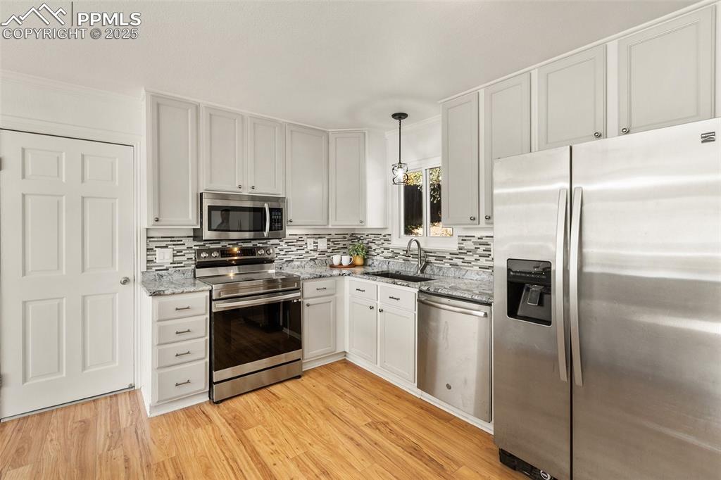 Image 24 of 47: Kitchen with appliances with stainless steel finishes, pendant lighting, de