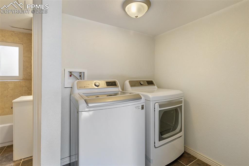 Image 25 of 47: Laundry area featuring washer and dryer and dark tile patterned flooring