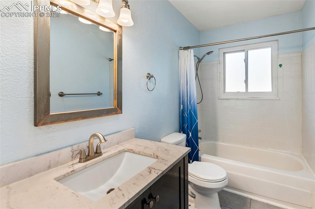 Image 34 of 47: Full bath featuring shower / bath combo with shower curtain, vanity, a text