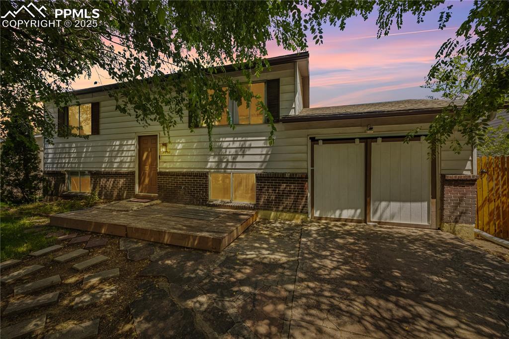 Caption: View of front of property with a deck and brick siding