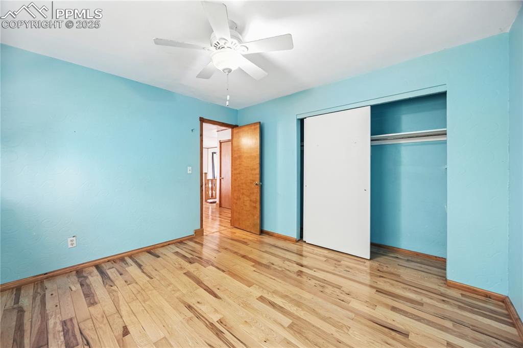 Image 12 of 23: Unfurnished bedroom with wood finished floors, a ceiling fan, and a closet