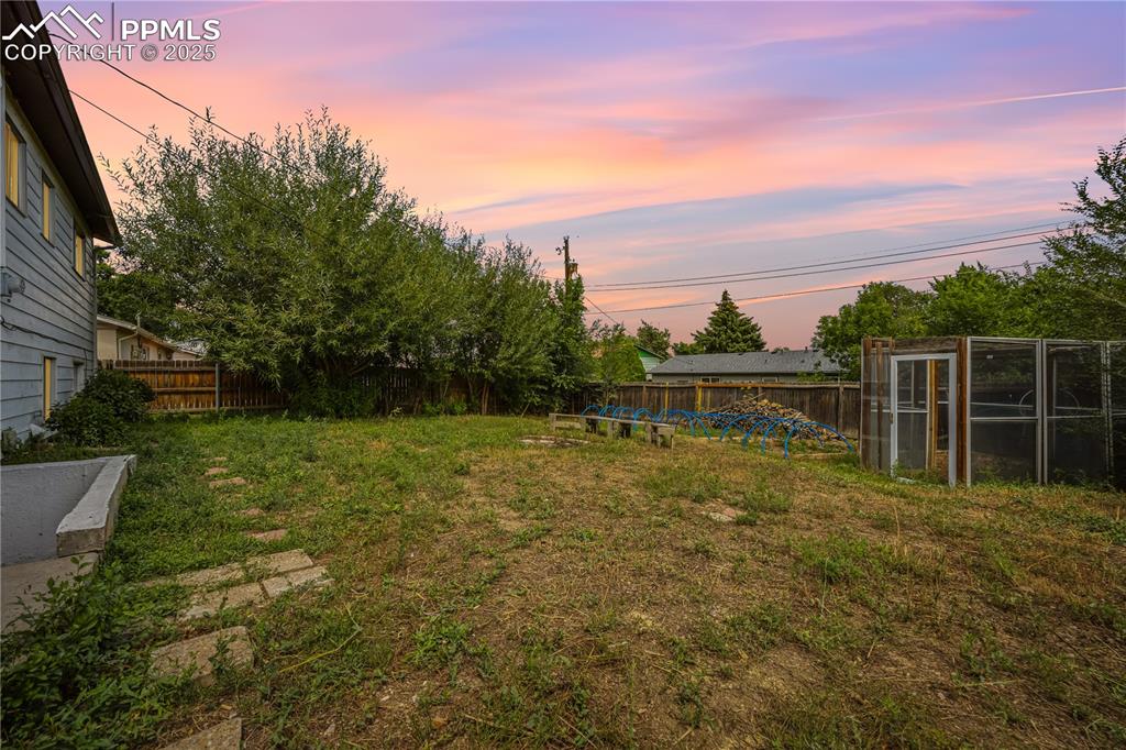 Image 23 of 23: Fenced backyard with an outbuilding