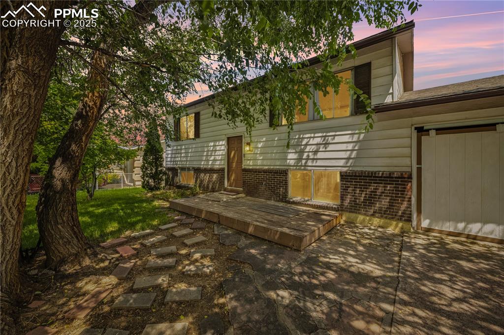 Image 3 of 23: View of front of home with a wooden deck, a lawn, and a garage