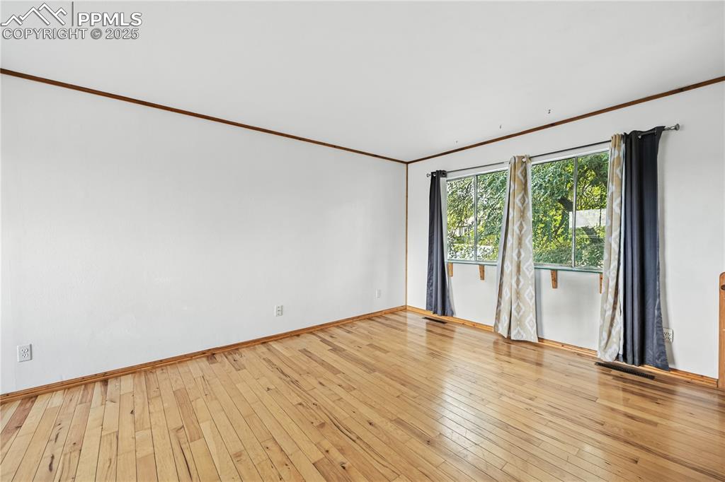 Image 6 of 23: Empty room with crown molding and wood-type flooring
