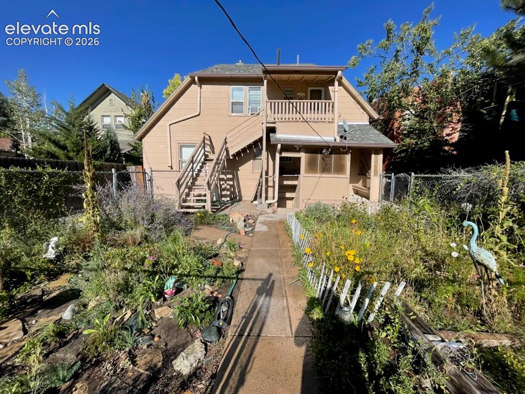 Caption: Two-story home with neutral-toned siding, a second-floor balcony, exterior staircase, and a covered 