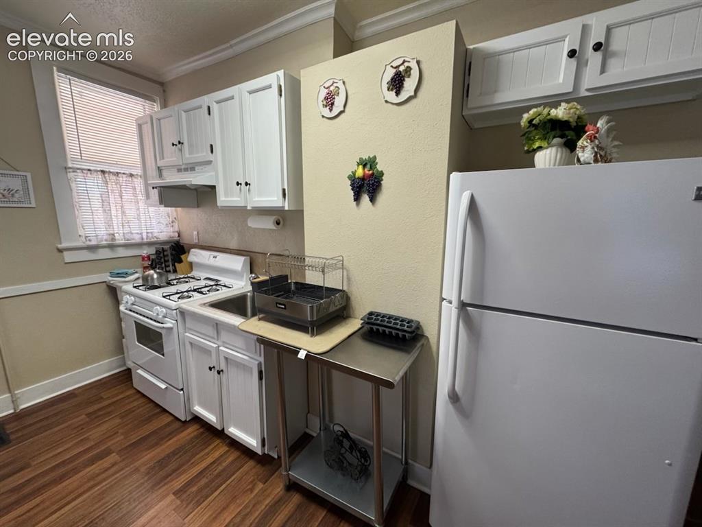 Image 10 of 27: White cabinetry with black hardware, wood-finish flooring, white gas range 