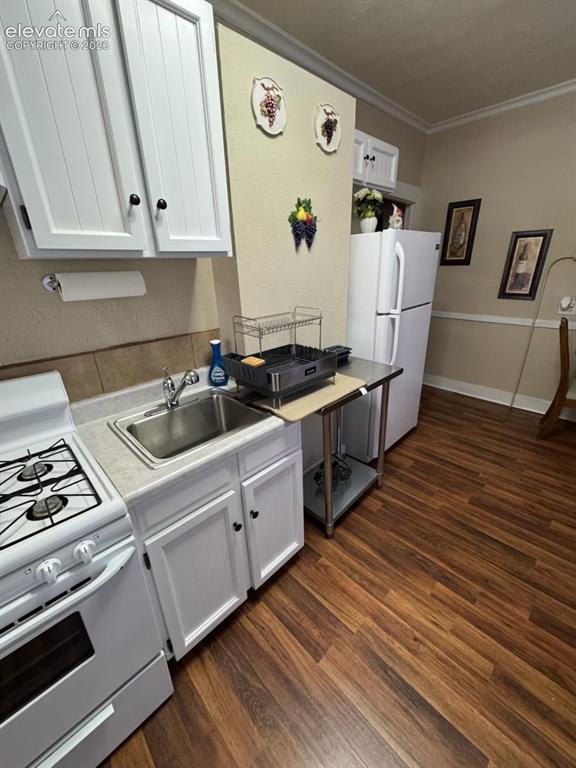 Image 11 of 27: White cabinetry with dark hardware, stainless steel sink, white freestandin