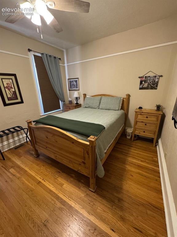Image 12 of 27: Wood-finish flooring, ceiling fan with integrated lighting, window with bli