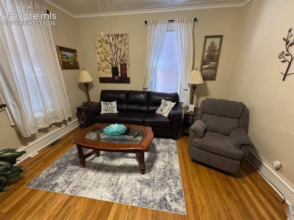 Image 13 of 27: Hardwood flooring, crown molding, and substantial window trim