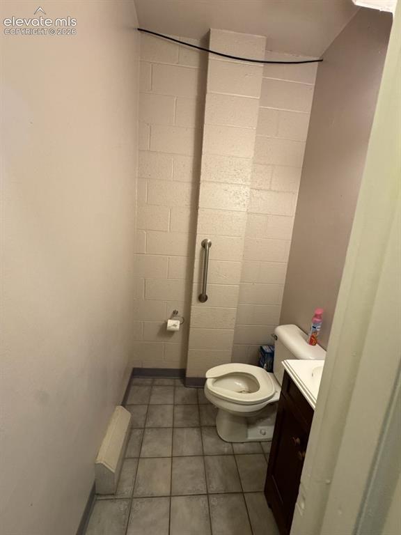 Image 17 of 27: Tile flooring, wall-mounted grab bar, and a compact vanity with an integrat