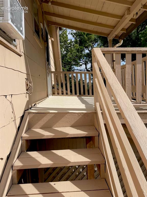 Image 23 of 27: Covered porch with wooden stairs and railing