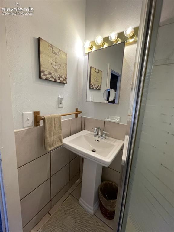 Image 24 of 27: Pedestal sink with chrome faucet, integrated mirror, four-bulb vanity light