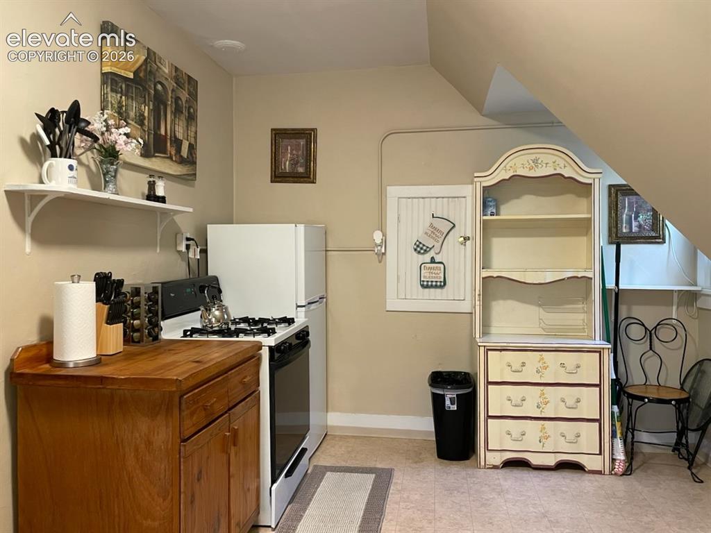 Image 26 of 27: Compact kitchen space with a gas range and a full-size refrigerator