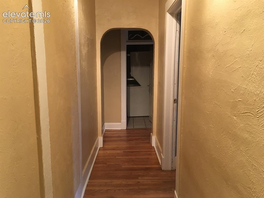 Image 7 of 27: Archway entry with wood-finish flooring and textured walls