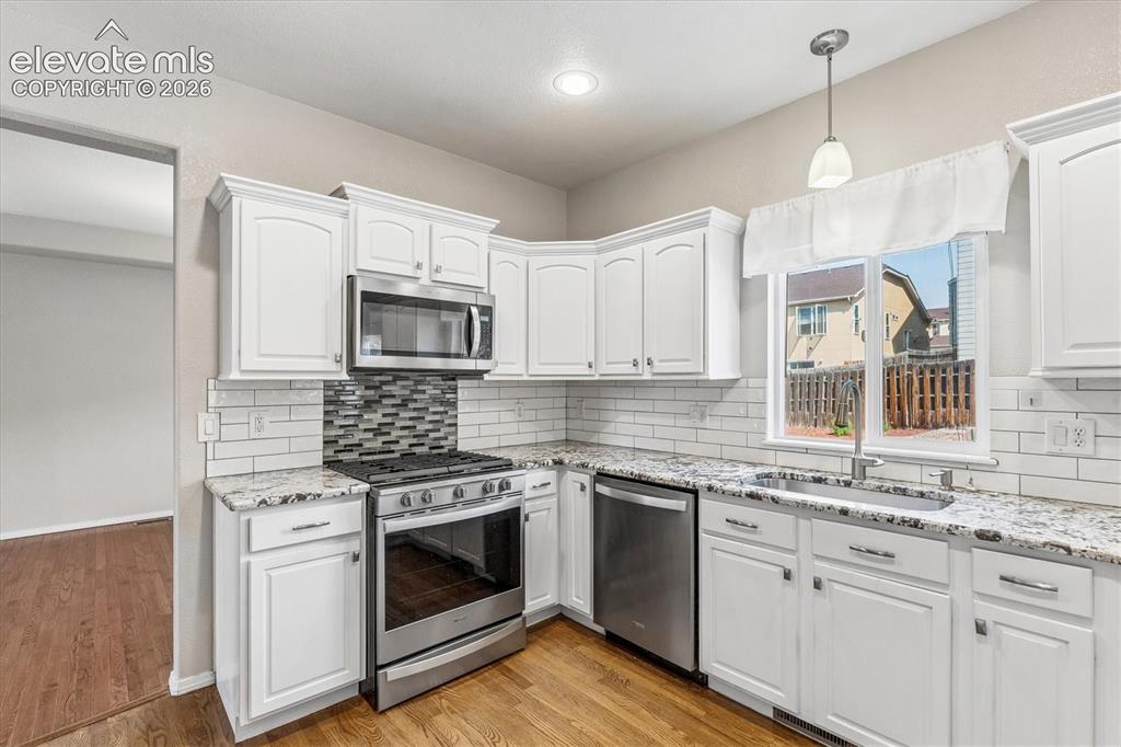 Image 10 of 46: Kitchen featuring white cabinetry, granite countertops, and stainless steel
