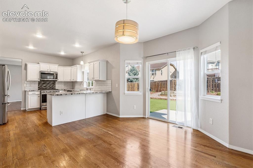 Image 13 of 46: Breakfast area and breakfast bar with sliding door to backyard