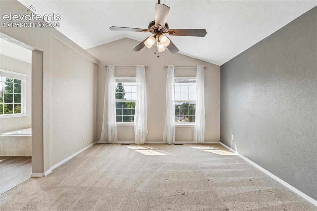 Image 17 of 46: Primary bedroom with vaulted ceilings, dual windows, and a ceiling fan with